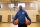 Un homme est debout sur un terrain de basket et tient deux ballons de basket.